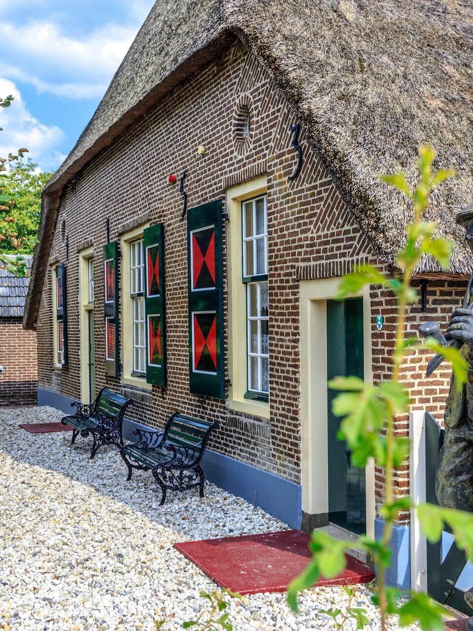 Boerderij met een rieten dak en een standbeeld van een boer