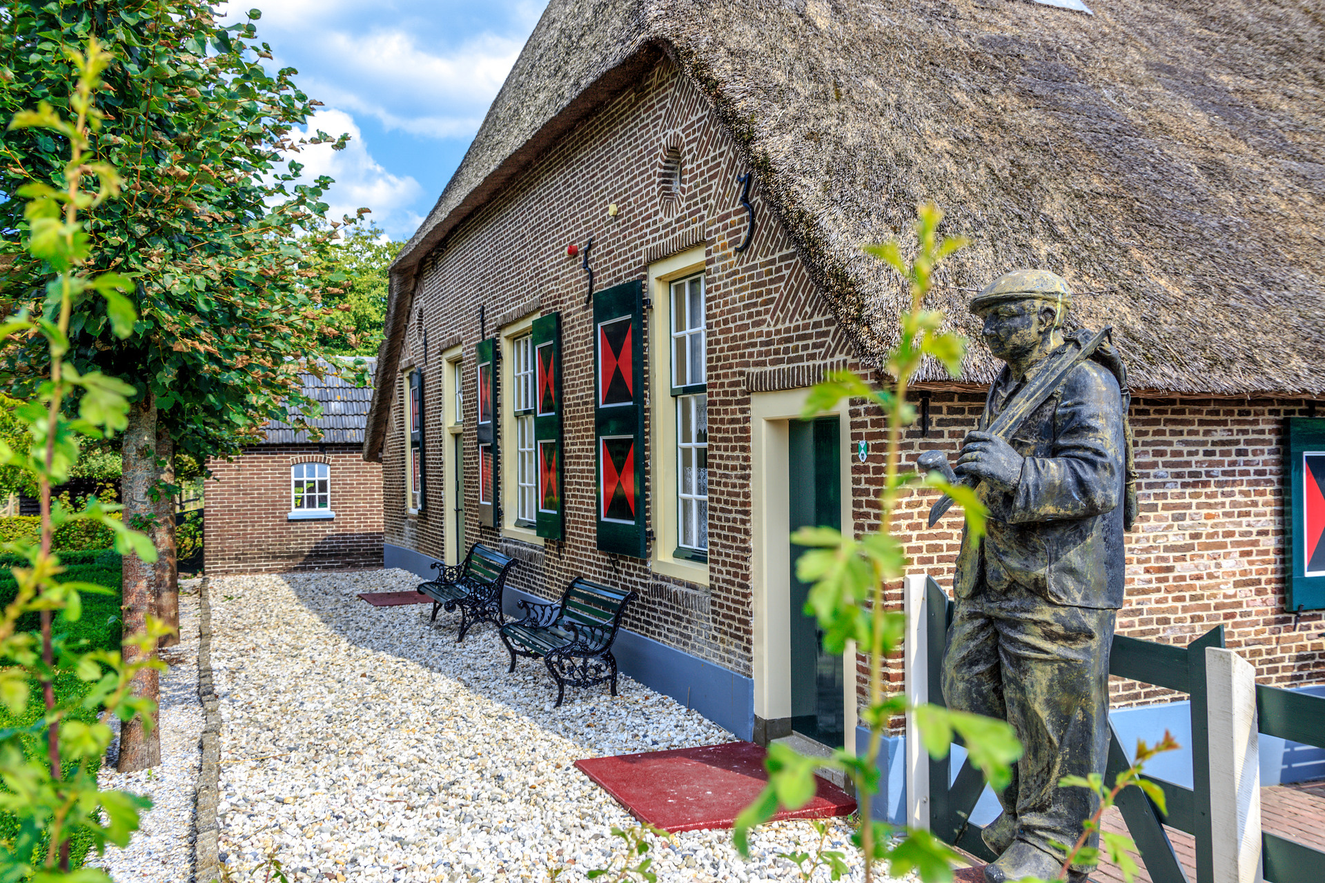 Boerderij met een rieten dak en een standbeeld van een boer