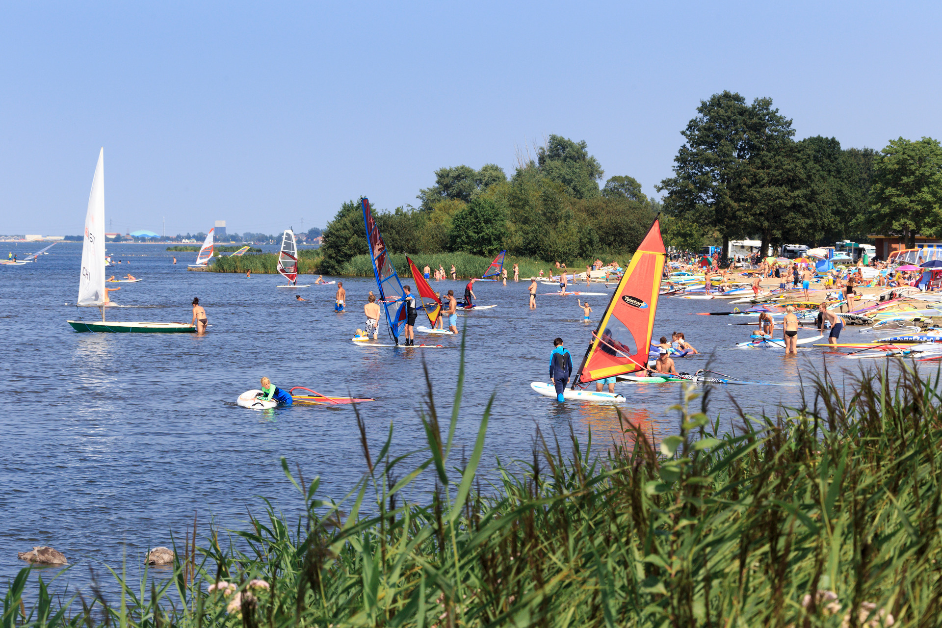 Mensen op een zomerse dag aan het surfen of liggend aan het strand van Strand Horst in Ermelo