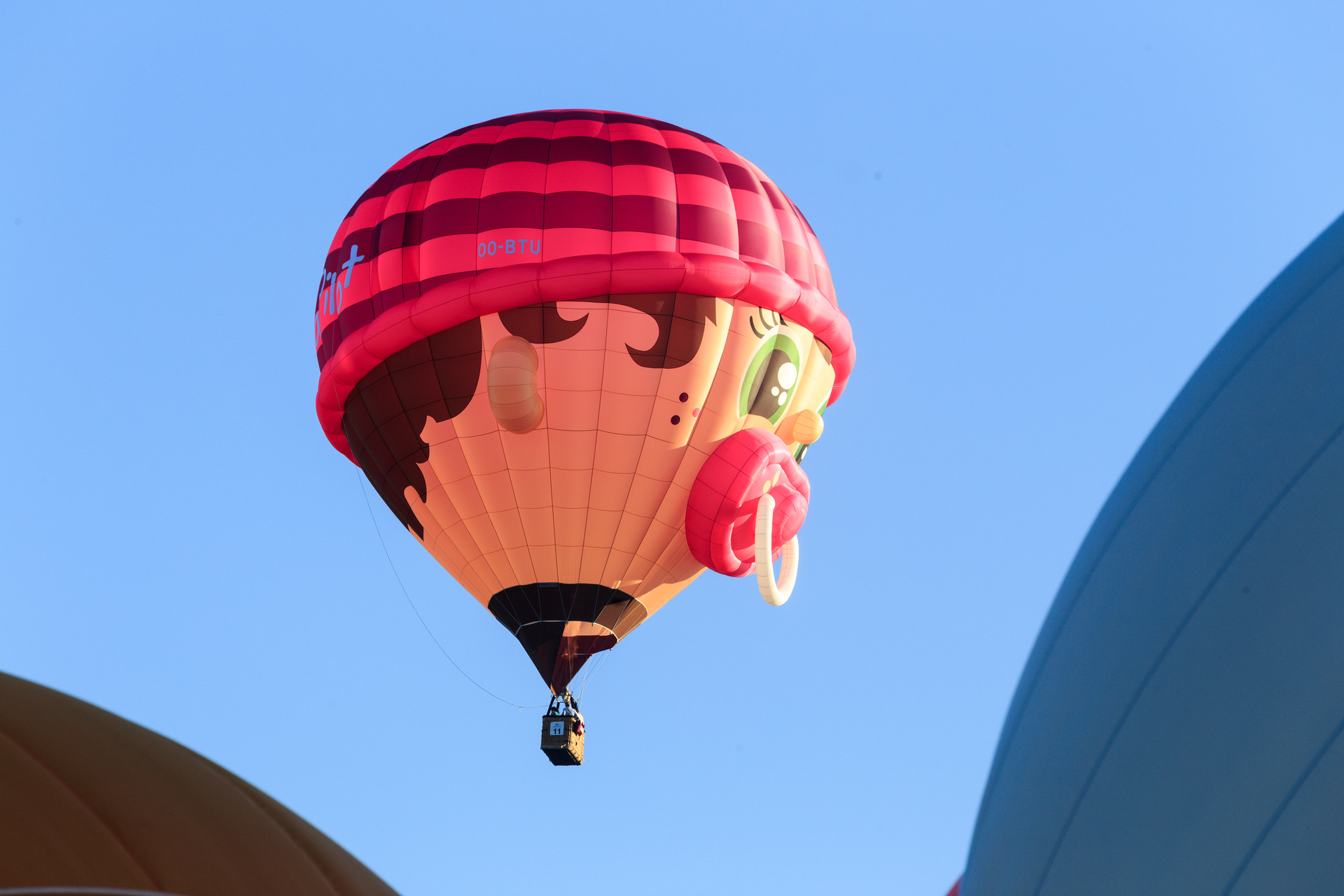 Een luchtballon met een gezichtje vliegt door de lucht bij Ballonfiësta, Barneveld