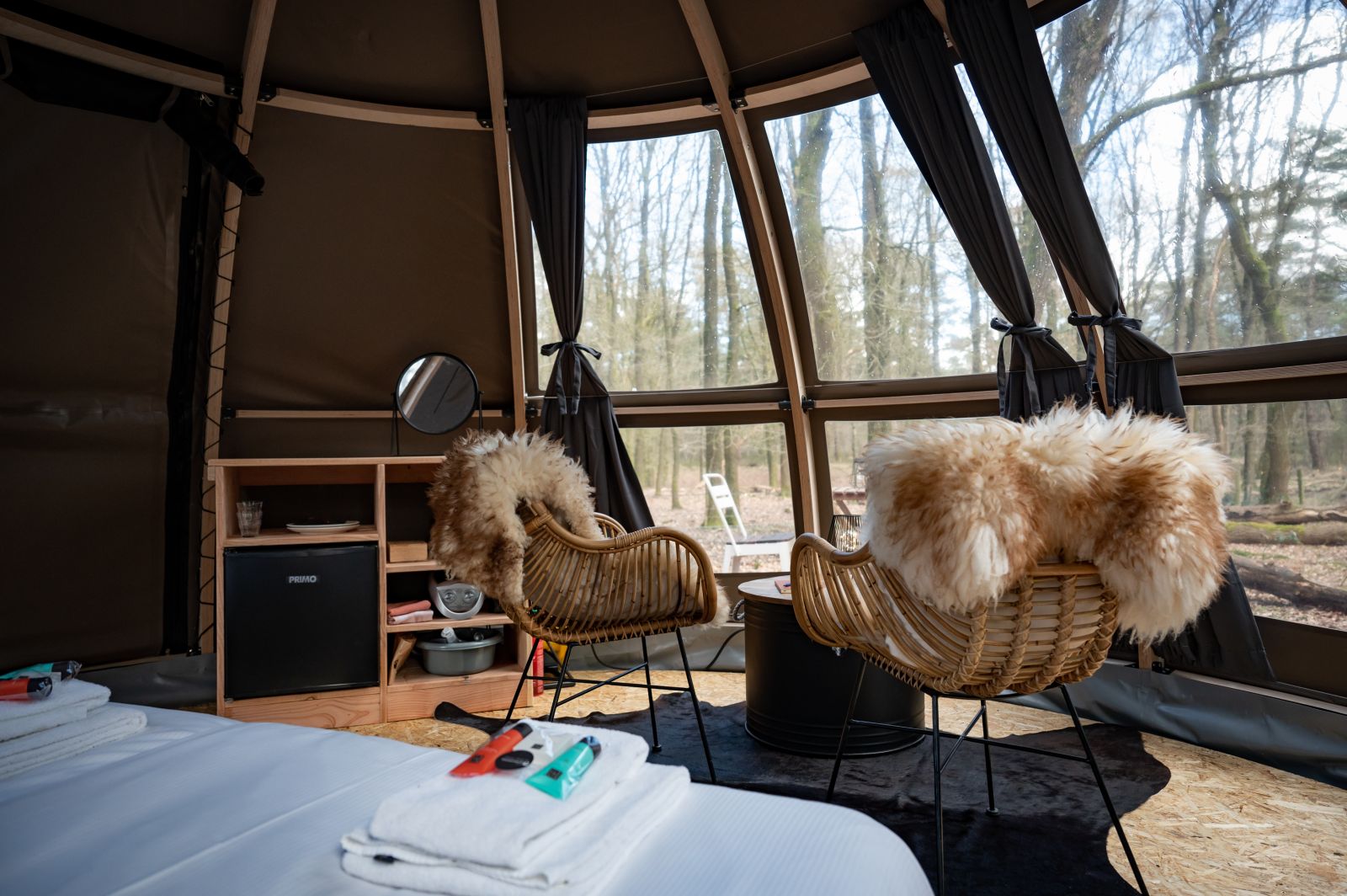 Bed en stoelen met bont in een luxe glamping tent in de bossen bij Elspeet