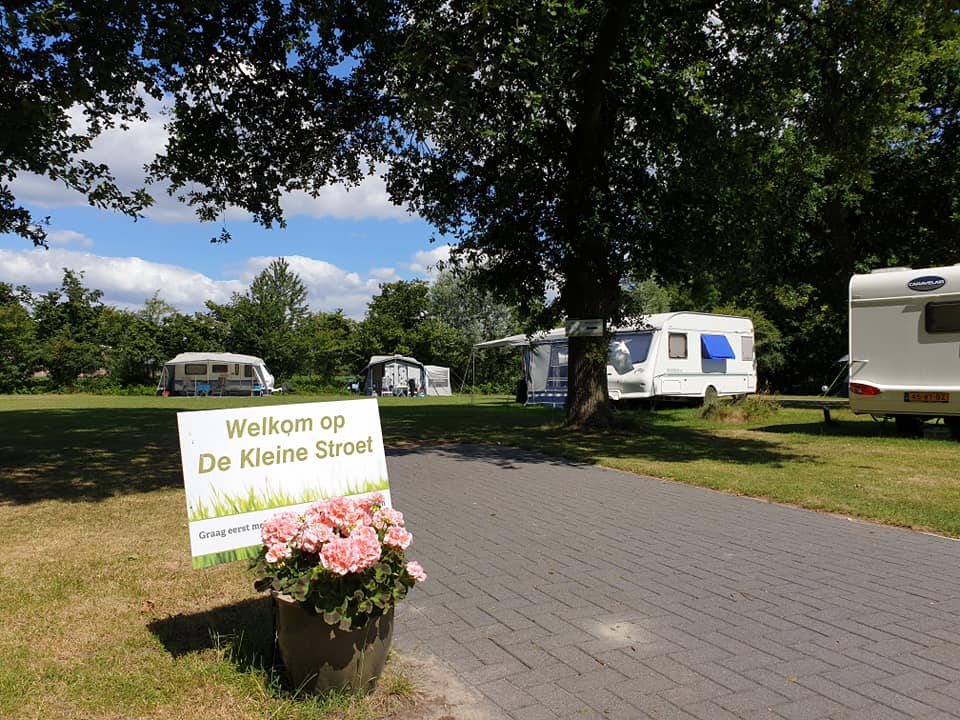 Welkomsbordje voor de camping De Kleine Stoet met caravans in de achtergrond