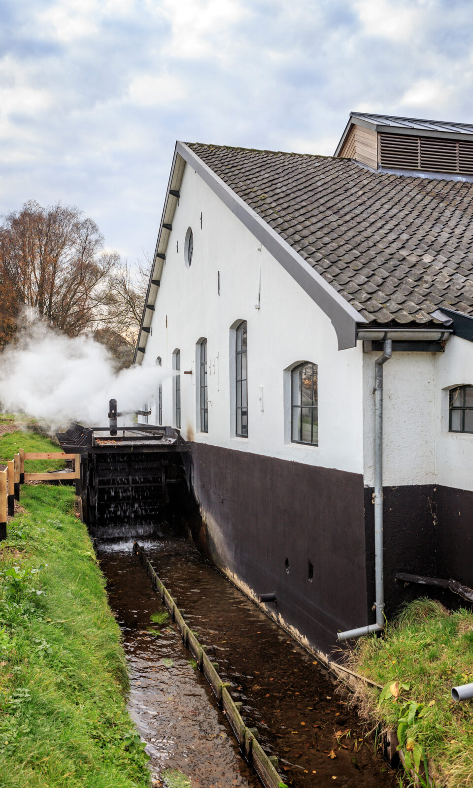 Een gebouw met een wit dak aan beek met stoom