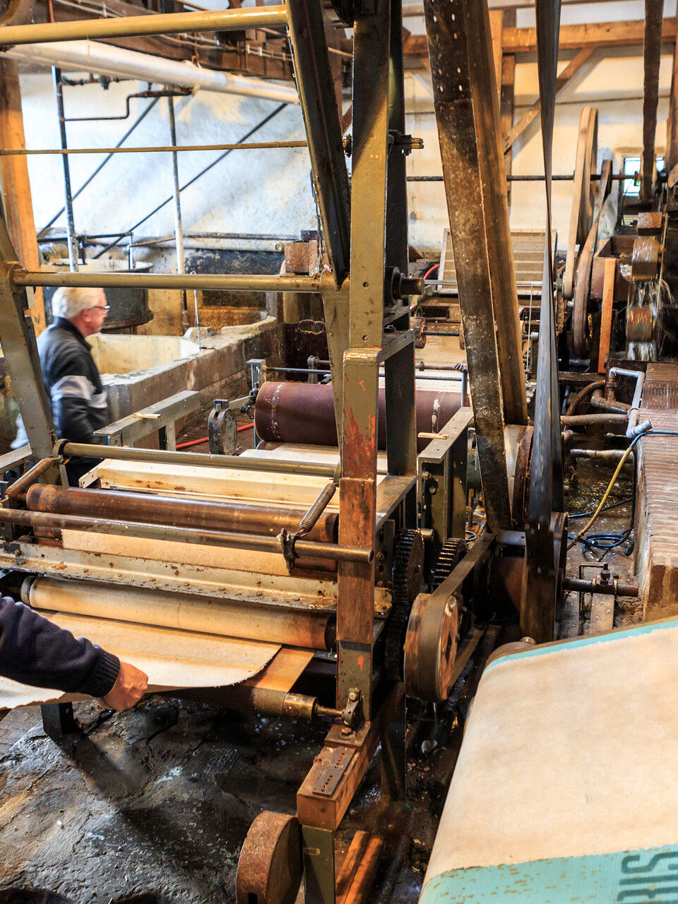 Man maakt papier in molen in houten machine