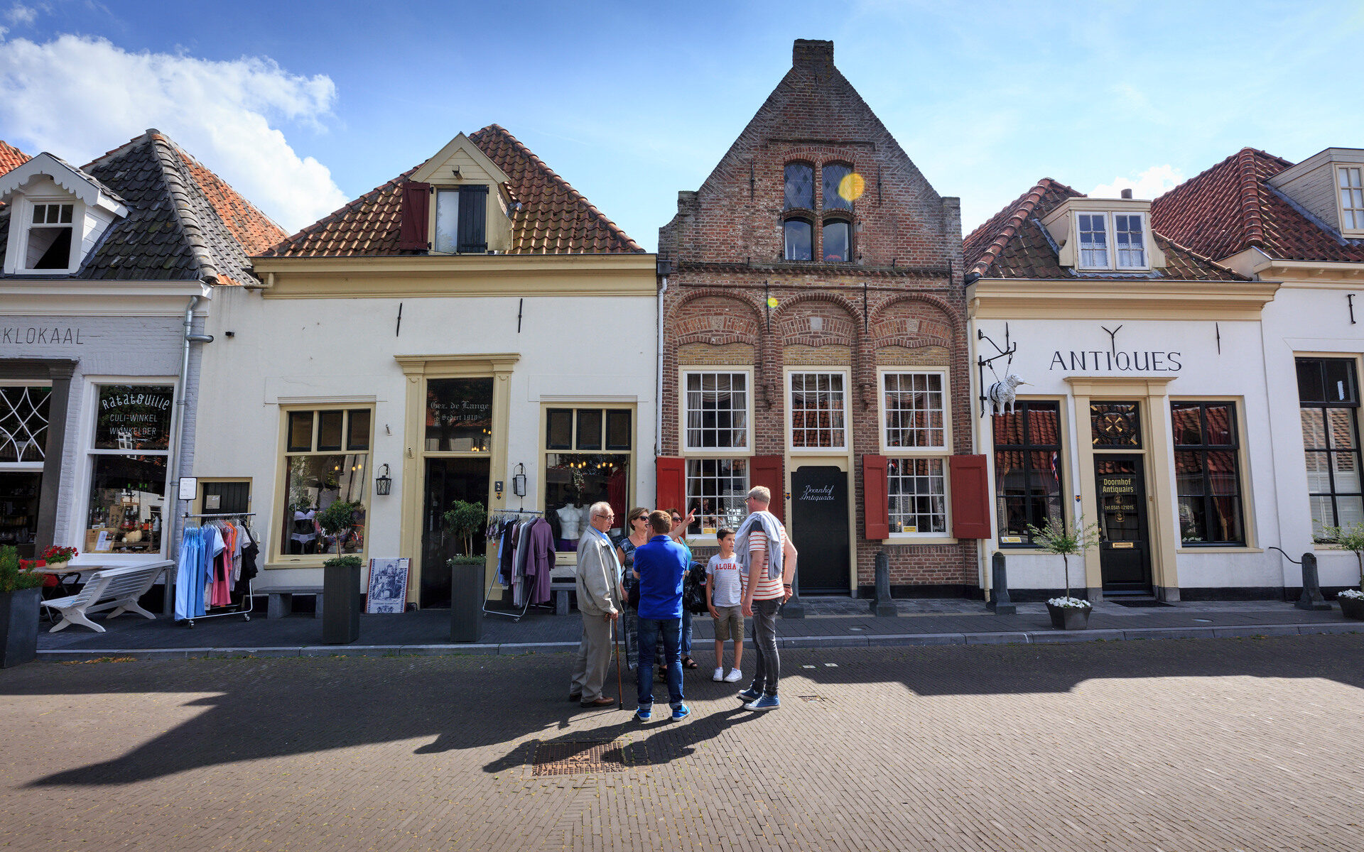 Winkelstraat in een hanzestad waar een groepje mensen in de straat staat te overleggen