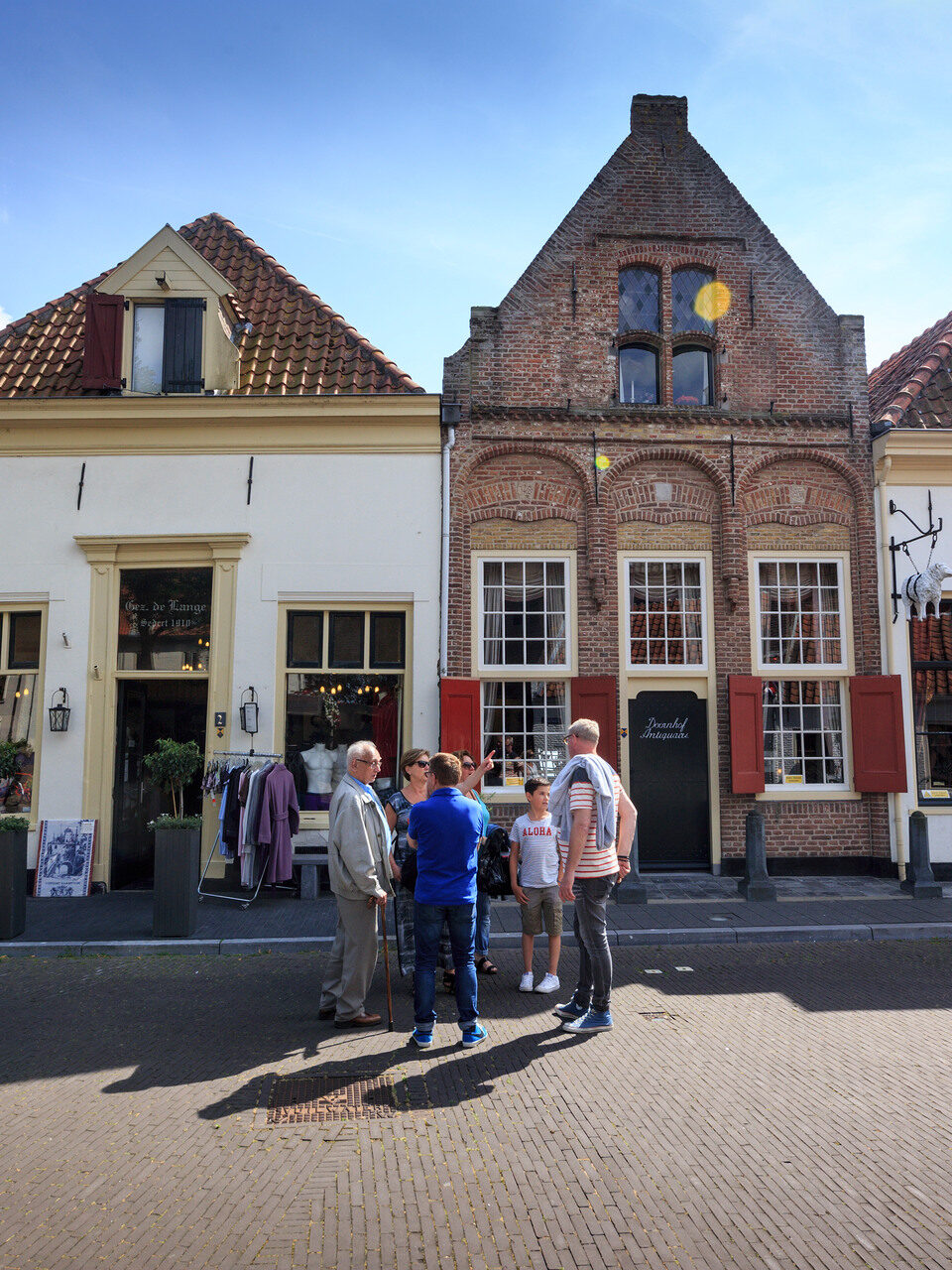 Winkelstraat in een hanzestad waar een groepje mensen in de straat staat te overleggen