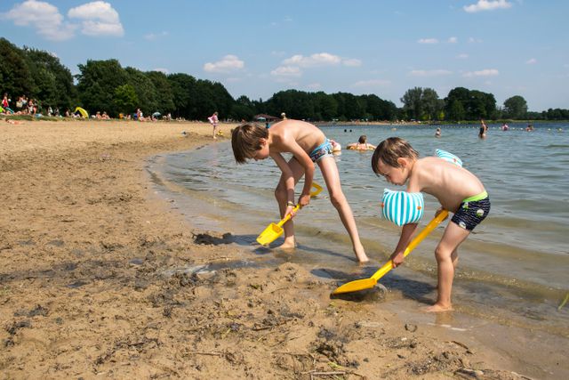 Twee jongetjes in zwembroek scheppen in de branding op het Heerderstrand.