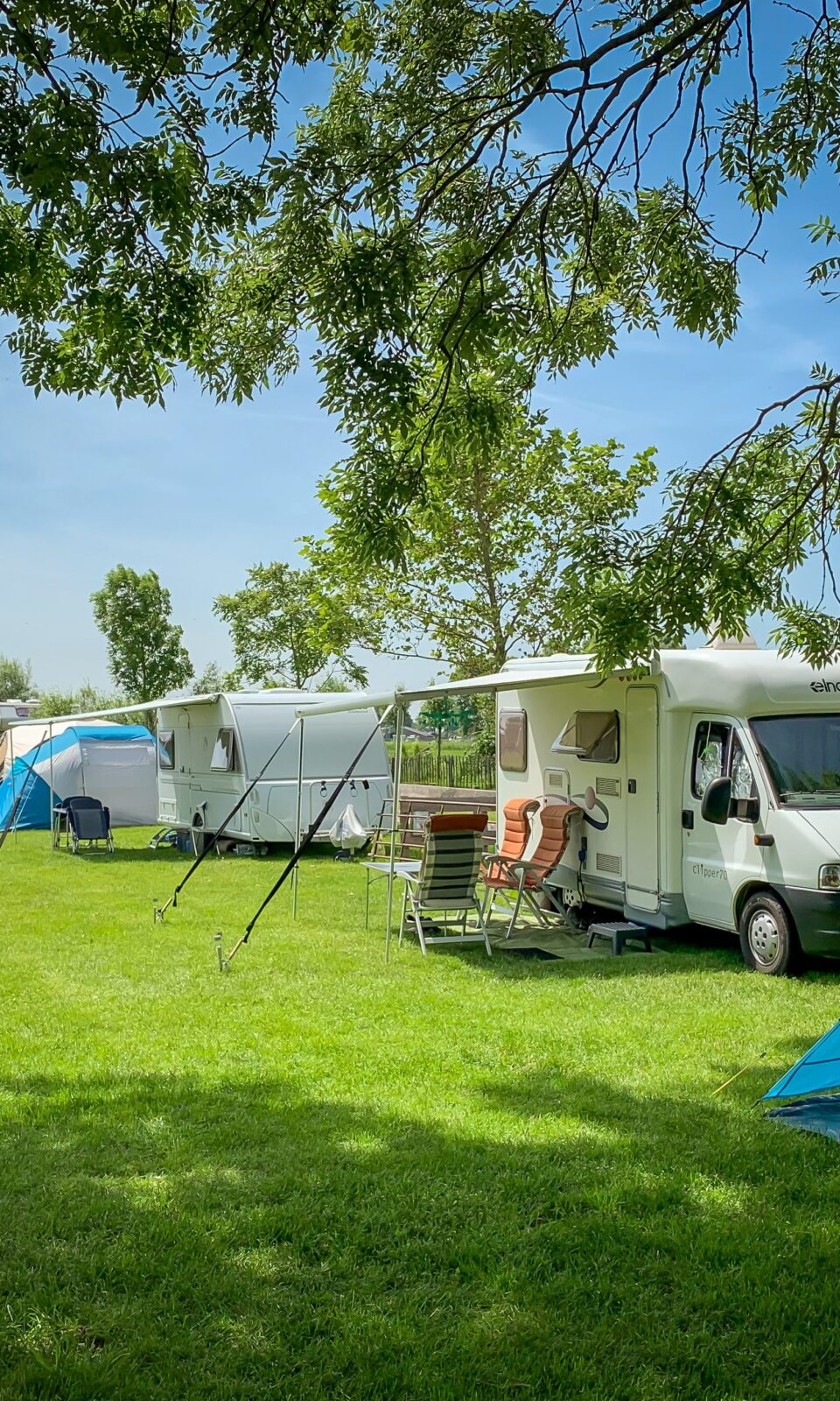 An image of a campsite with a tent, a campfire, and people enjoying nature