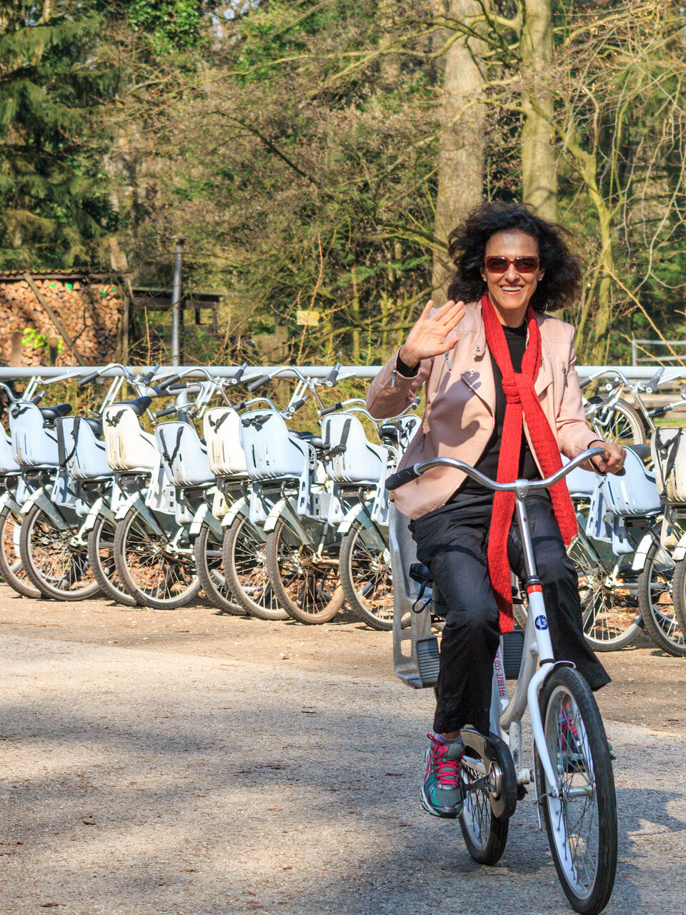 Vrouw op de fiets voor een rek met witte fietsen