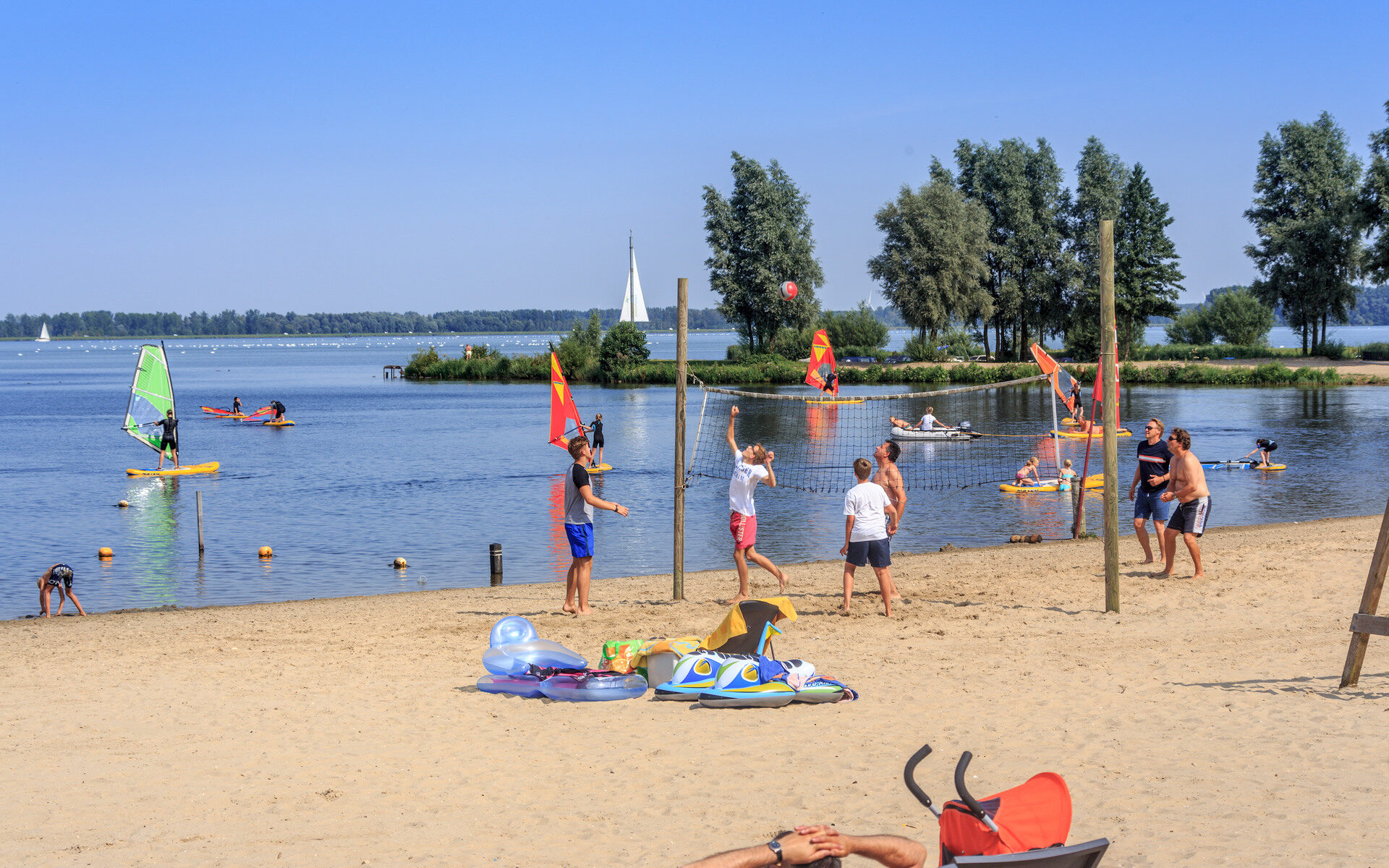 Mensen genieten van het mooie weer op het strand aan het Veluwemeer.