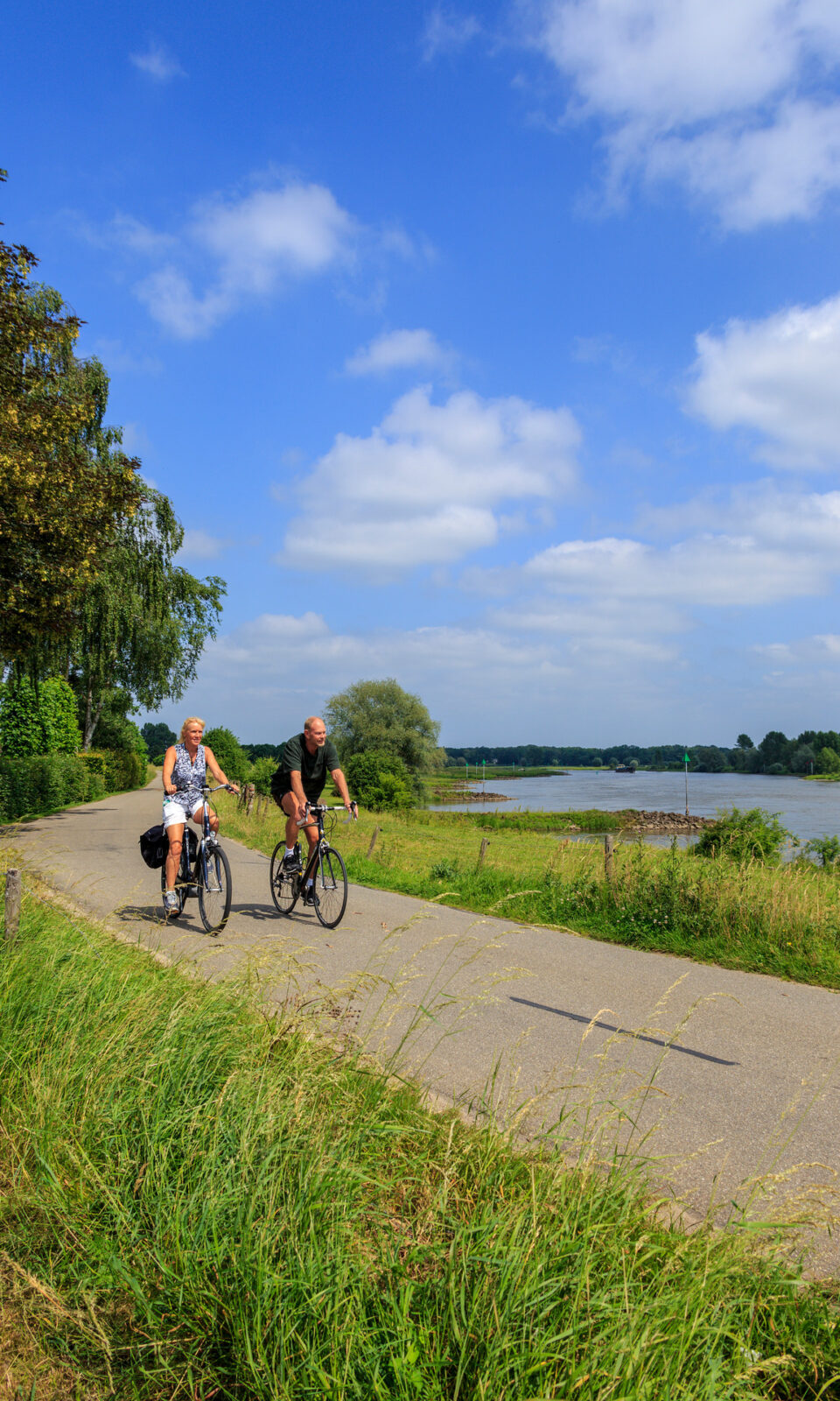 Man en vrouw fietsen op de dijk bij Wilp