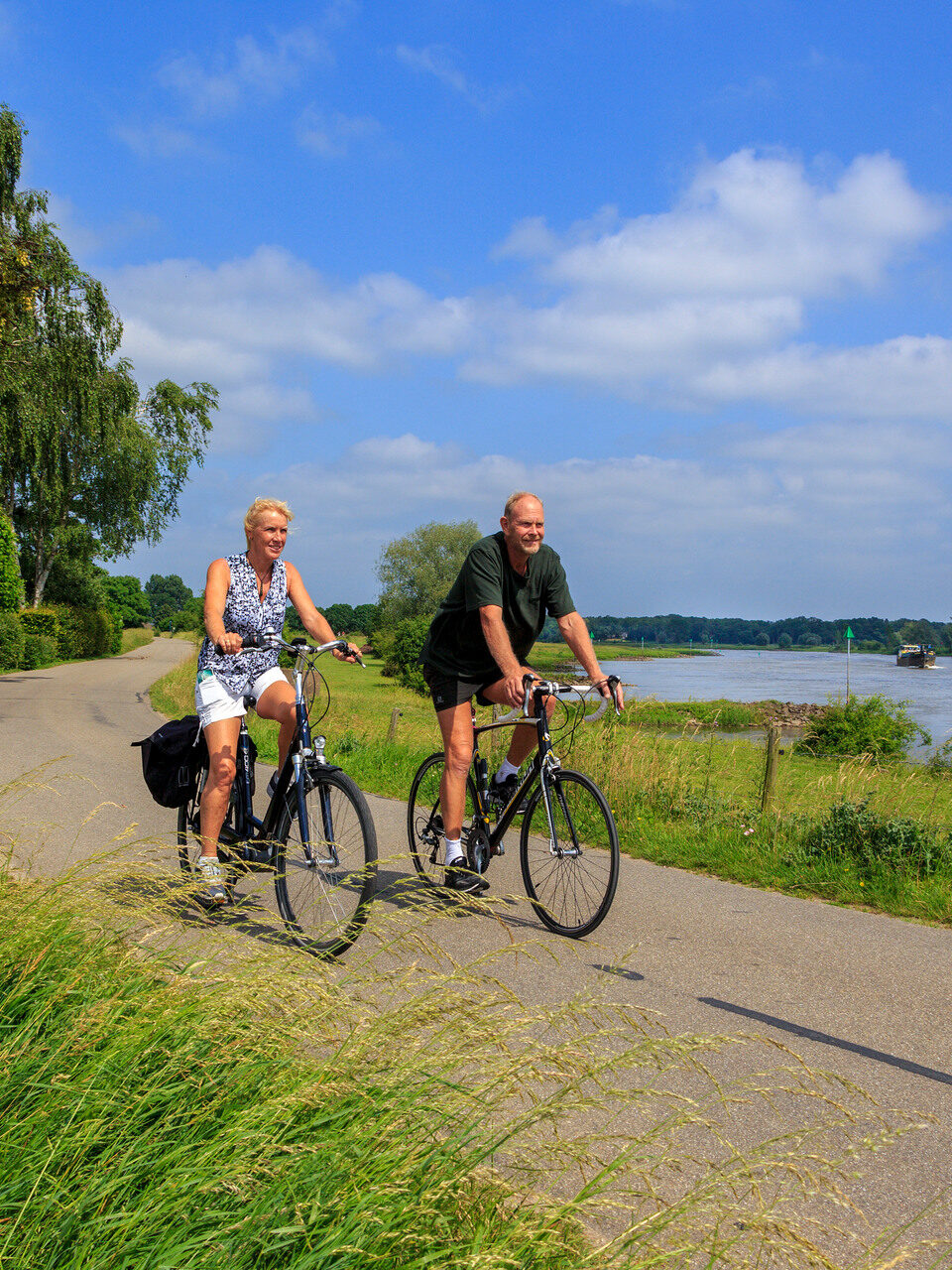 A man and a woman biking along the IJssel River.