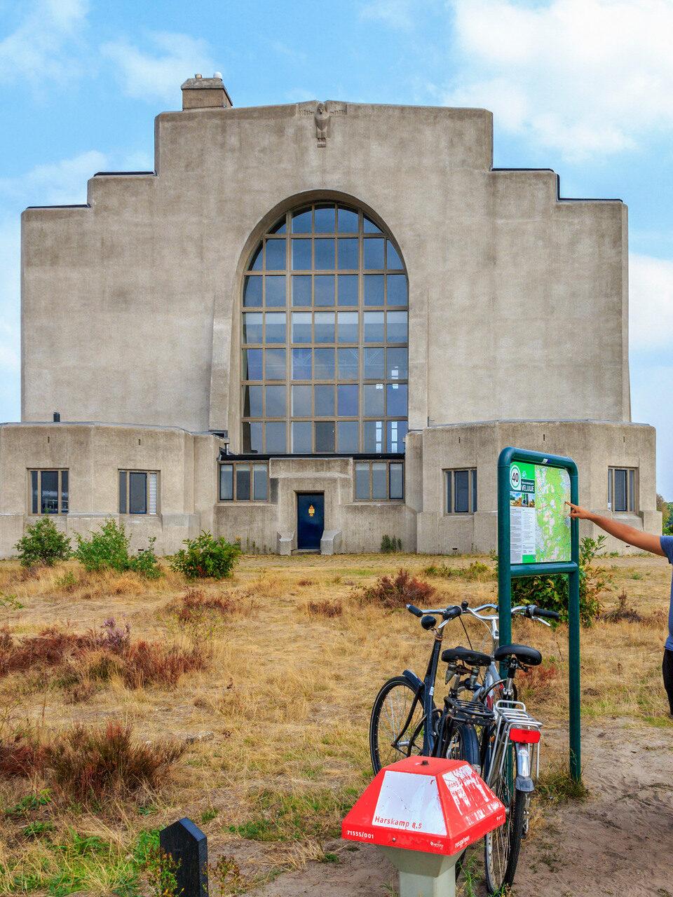Een man en een vrouw staan naast een fiets en kijken naar een routebord.