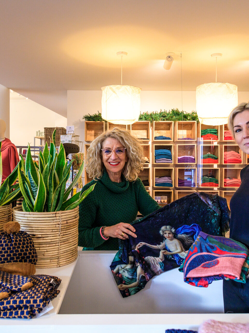 Twee verkoopmedewerkers lachend naar de camera in een kledingwinkel van Apeldoorn