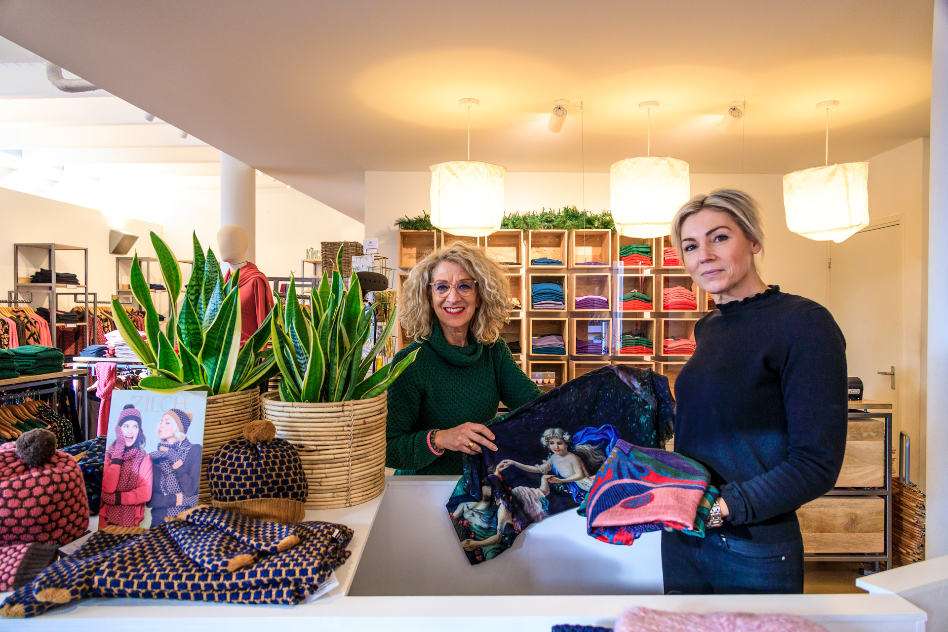 Two sales assistants smile at the camera in an Apeldoorn clothing shop