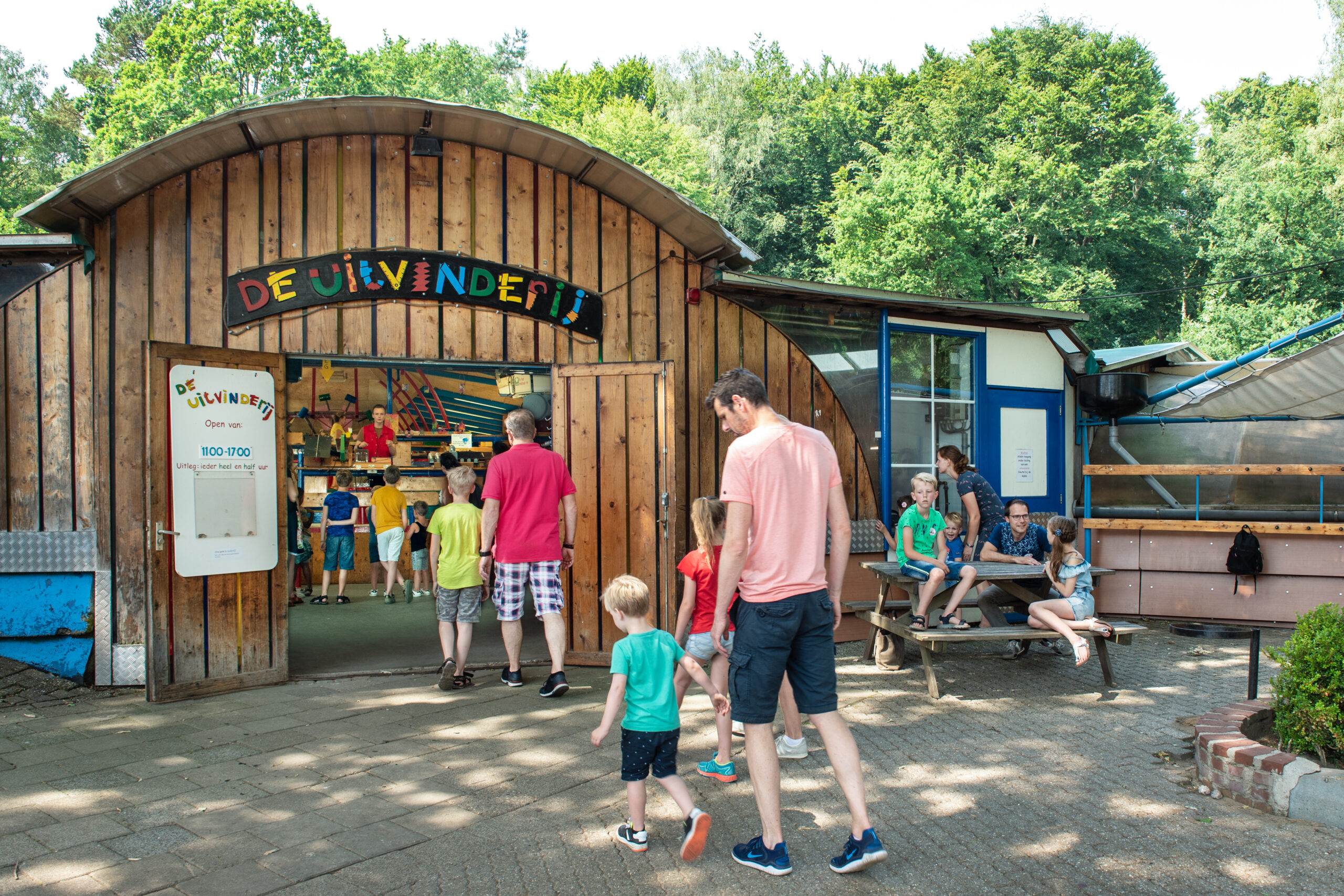 Man met jonge kinderen voor ingang van de Spelerij - Uitvinderij