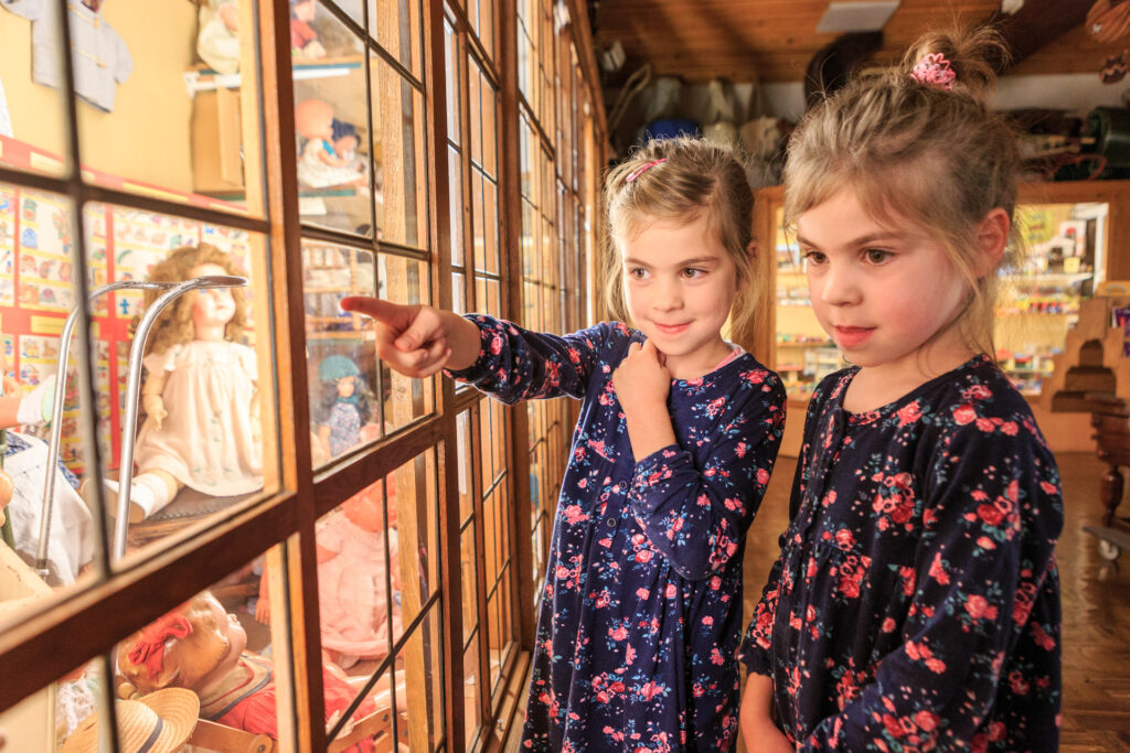 Twee meisjes bekijken poppen in een speelgoedmuseum