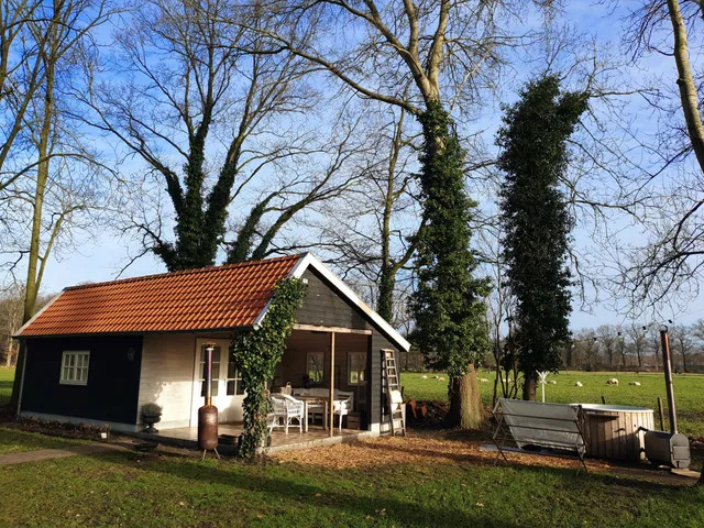 Een Bed en Breakfast met weiland en bomen op de achtergrond