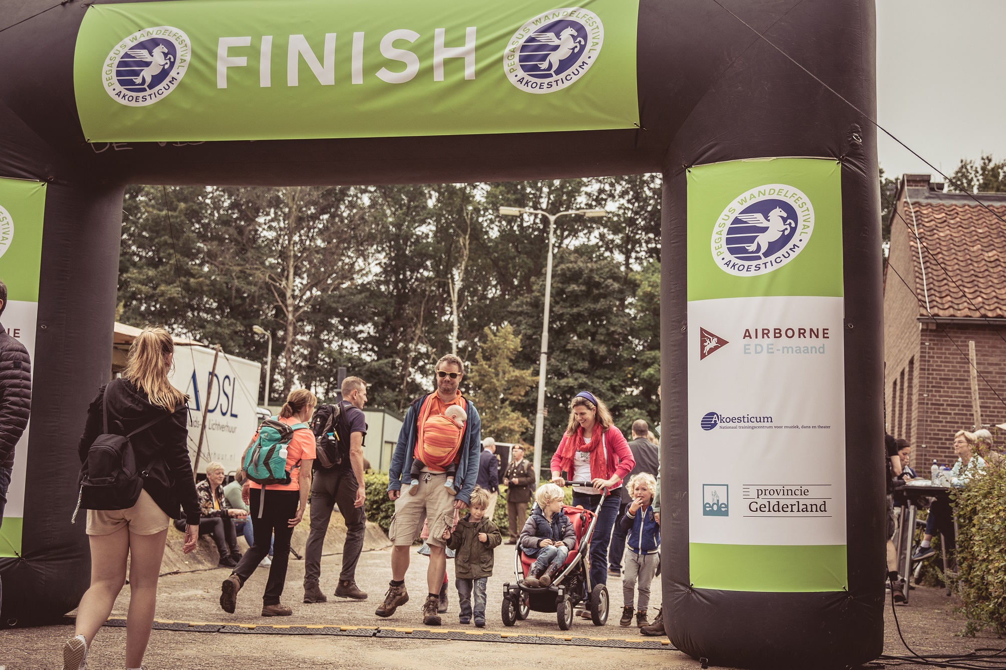 Een groep wandelaars loopt onder de finishboog door tijdens het Pegasus Wandelfestival