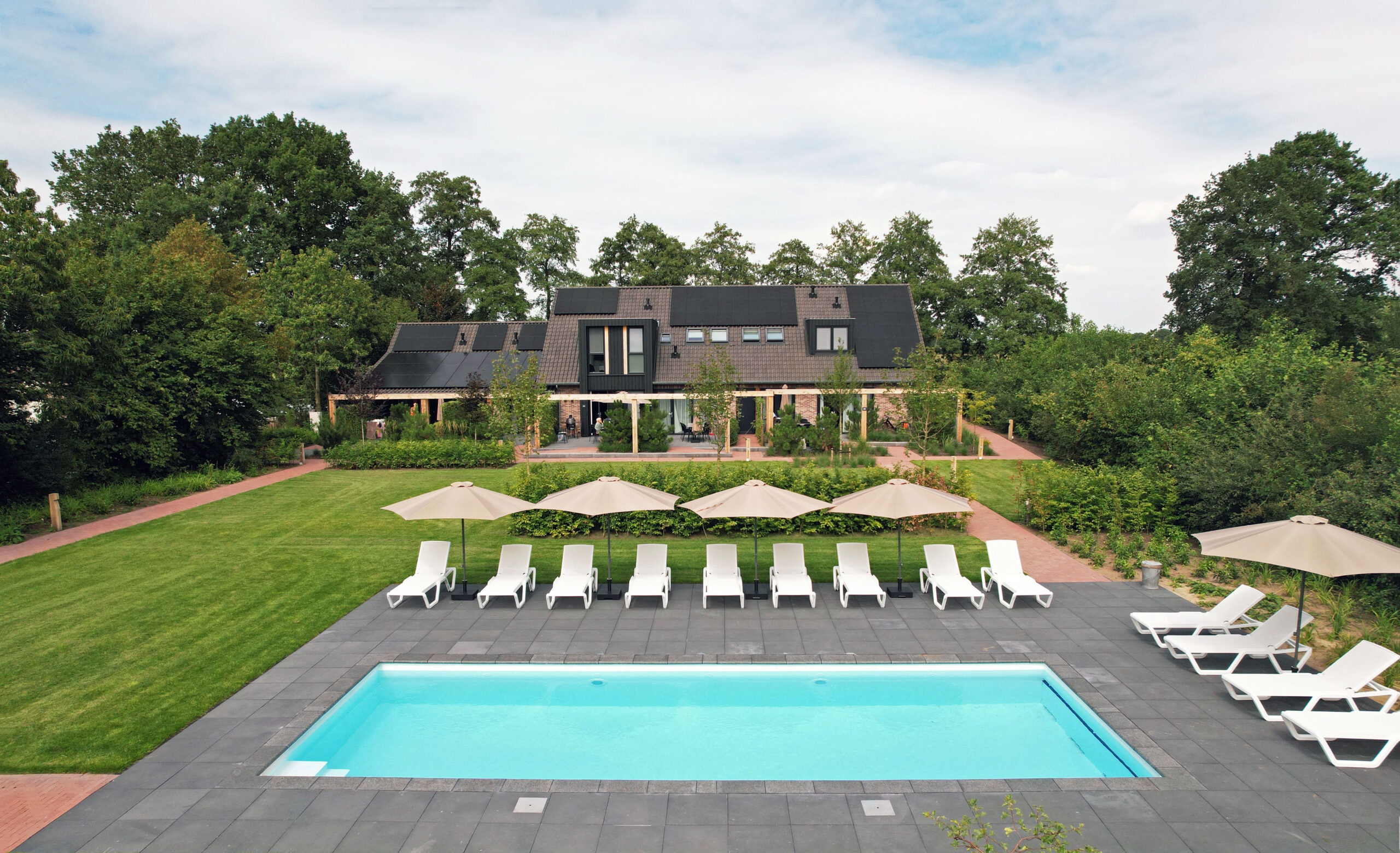 Buitenzwembad met ligstoelen en op de achtergrond een verblijfsaccommodatie