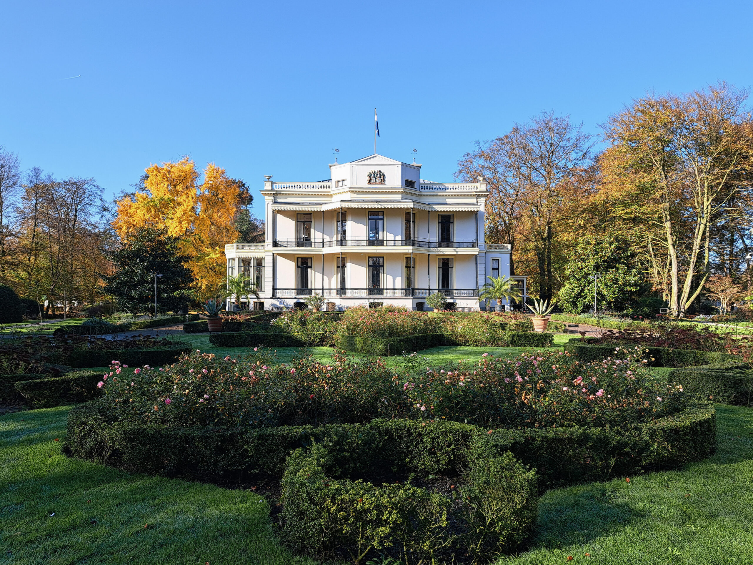 wit landhuis met herfstkleurige bomen ernaast