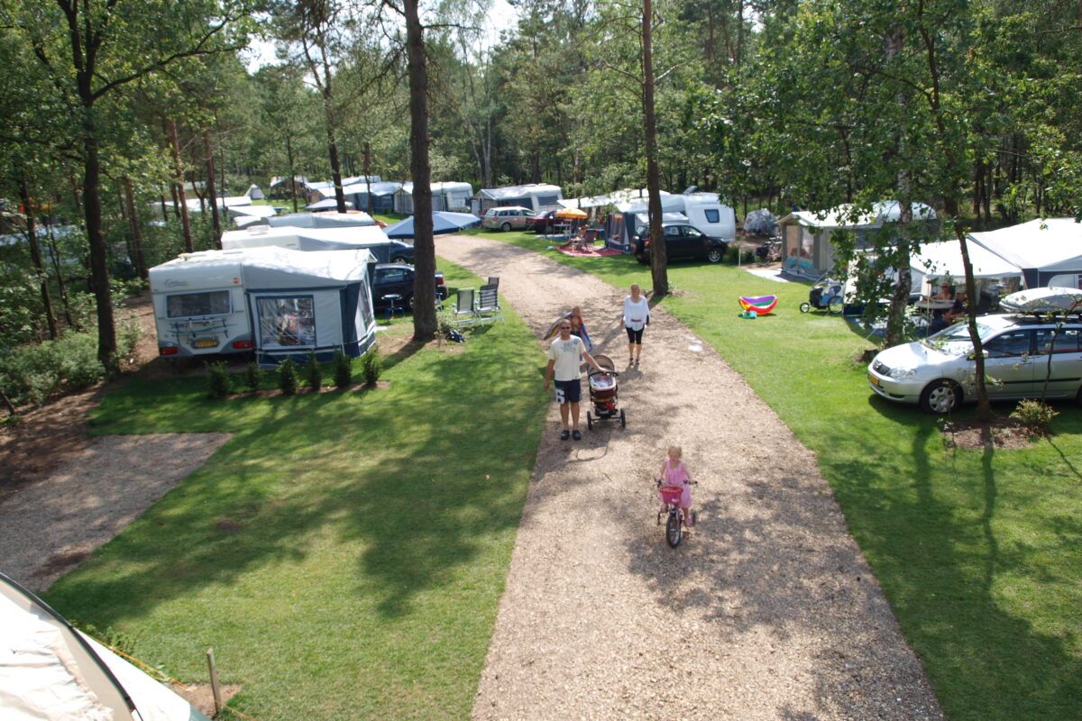 Mensen lopen op een pad tussen caravans en tenten