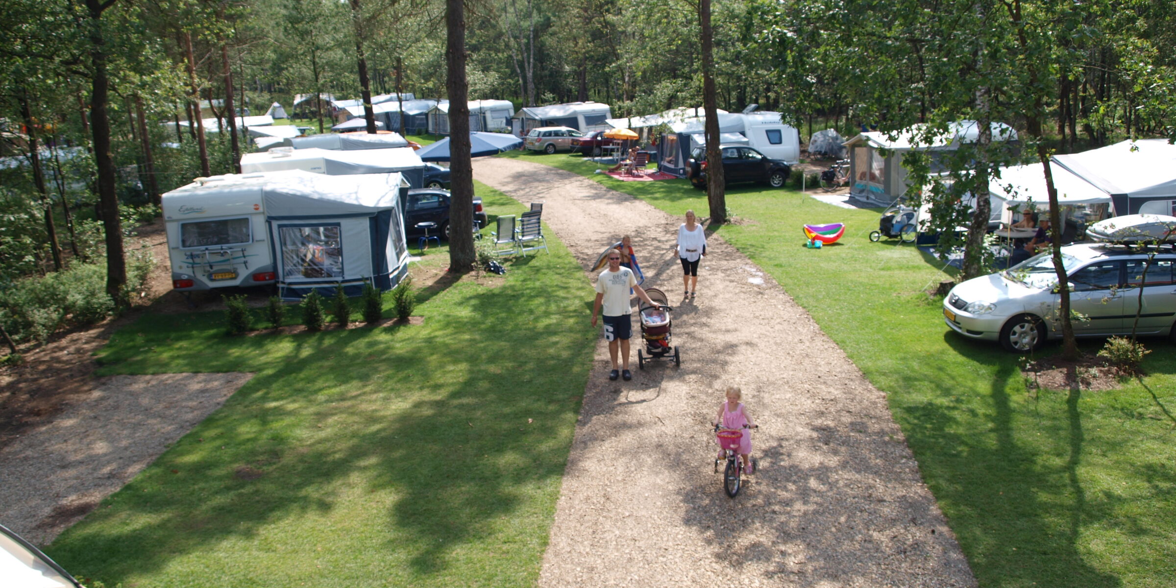 Mensen lopen op een pad tussen caravans en tenten